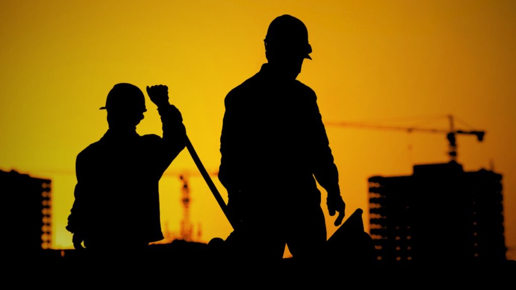 Two labours working, representing a unique combination of sunset and skip hire services in Manchester